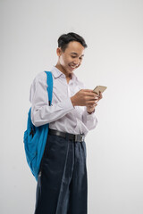 a boy wearing a junior high school uniform looking at a cellphone with a backpack on an isolated...