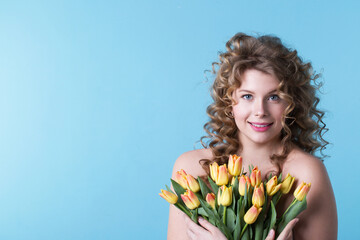 Obraz na płótnie Canvas Portrait of a pretty curly woman smiling with tulips. Happiness and holiday