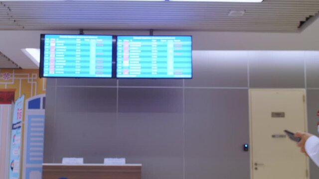 4K Asian tourist women wear protective fack mask with travel bag backpack checking timetable or schedule of flights in Airport COVID-19 Coronavirus pandemic. safe traveling and tourism