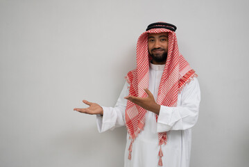an arabian young man in a turban smiling while standing looking at the camera with a hand gesture...