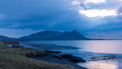 Scenic mountain landscape with dramatic sky and reflections in the lake in Iceland during night time.
