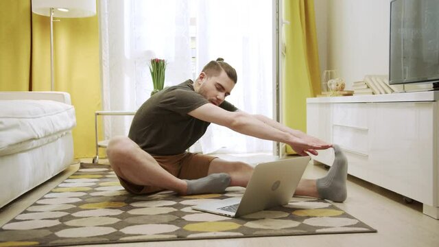 An attractive young man is making healthy exercises on the Internet 