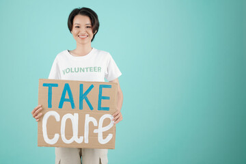 Cheerful young volunteer of community donation center holding take care placard