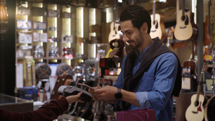 An upwardly mobile Muslim man using smart payment to pay for a product at a sale terminal with nfc identification payment for verification and authentication