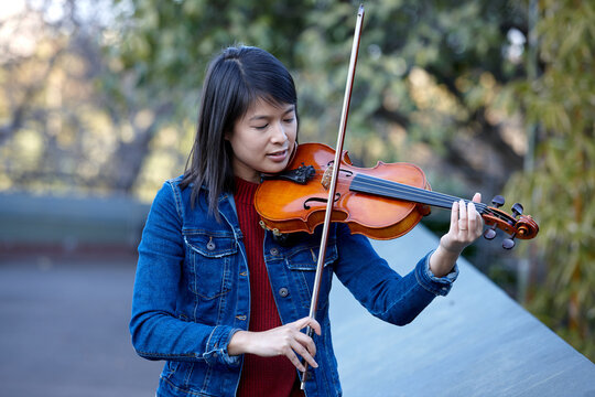Young Asian female violin player practising outdoors