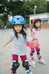 two asian girl going on her in-line skates in the park