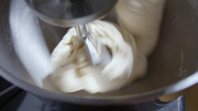4K Close up bread dough making process by using flour mixing machine. Machine knead bread dough. Homemade bread raw mix with small machine. Food concept.