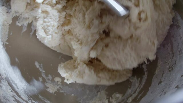 4K Close up bread dough making process by using flour mixing machine. Machine knead bread dough. Homemade bread raw mix with small machine. Food concept.