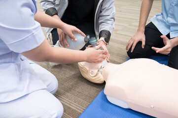 Demonstrating CPR (Cardiopulmonary resuscitation) training medical procedure on CPR doll in the class.Doctor and nurse students are learning how to rescue the patient.First aid for safe life concept. - Powered by Adobe