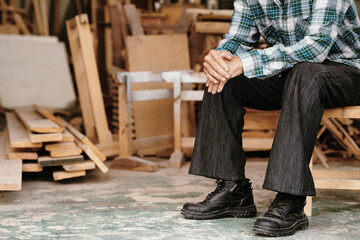 Cropped image of elderly carpenter resting after working with wood in his workshop