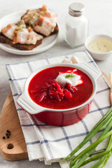 Delicious fresh red borscht, dark bread with lard and salt on kitchen table. 