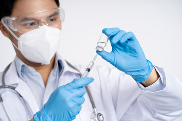 Health and medical concepts. Close-up photo of Asian doctor holding bottle of covid-19 vaccine and syringe. Preparing for human clinical trials.