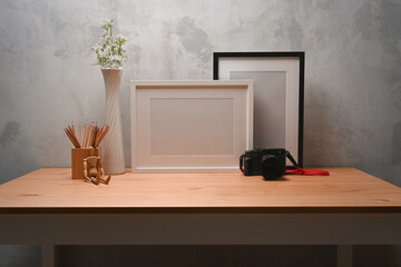 Empty photo frame, pencil holder and camera on wooden desk.