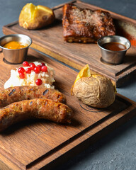 Fried sausages on a grill, grilled sausages with coleslaw salad, baked potato and sauce.