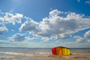 A multi-colored kite lies on the water in calm weather.