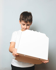 Small boy opening white pizza box over white background. Copy space banner. Junk food, fast food concept.