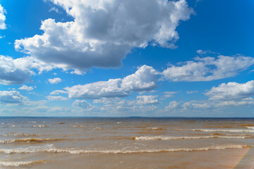 Fototapeta na wymiar The sea shore, waves on the water and clouds in the sky