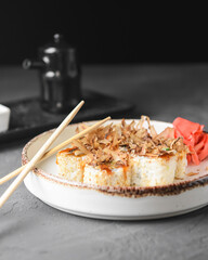 Tuna sushi in white dish served with soy and wasabi sauce, pickled ginger. Sushi set with tuna shavings on top.