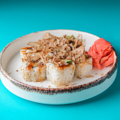 Tuna sushi in white dish served with wasabi sauce, pickled ginger. Sushi set with tuna shavings. Over blue background.