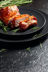 Grilled pork ribs on a black plate.