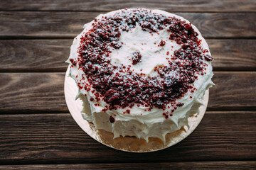 'Red Velvet' Holiday cake decorated with red sprinkles on a wooden table.