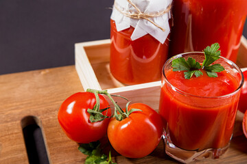 Tomato juice in a glass and fresh tomatoes on the table