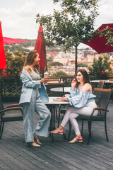 Obraz premium two young women friends at a cafe having breakfast, discussing the news, laughing. females in the cafe drink cocktails.