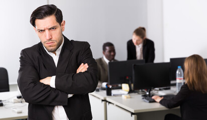 Young businessman standing in office on backround with with working colleagues
