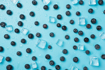 Top view photo of scattered blueberries ice cubes and drops on isolated light blue background