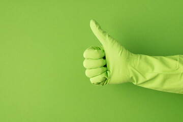 Profile photo of hand in green glove making thumb-up on isolated green background with copyspace - obrazy, fototapety, plakaty