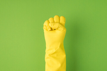Above photo of hands in yellow gloves making the gesture as fist isolated on the green background