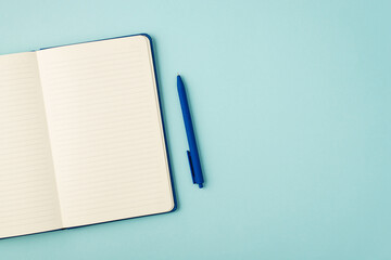 Top view photo of open blue reminder and pen on isolated pastel blue background with copyspace