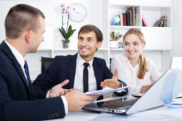 Cheerful coworkers chatting about business project in company office
