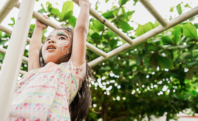 little healthy girl hanging on a bar in the playground
