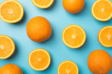 Top view photo of scattered cut and whole oranges on isolated pastel blue background