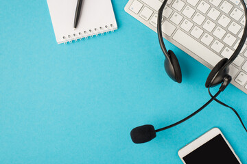 Top view photo of black headset on white keyboard pen on notebook and mobile phone on isolated...