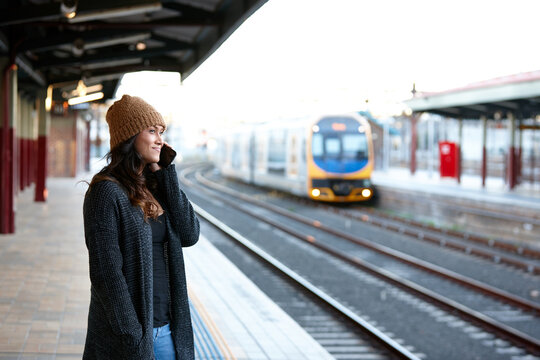 Asian woman waiting for train whilst talking on mobile phone