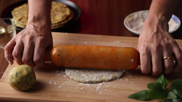 Preparation of Aloo Paratha or roti parantha chapati  4K slow motion video footage Punjab, North India. Female hand rolling whole wheat dough mashed potato stuffing rolling pin vegetarian Indian food 