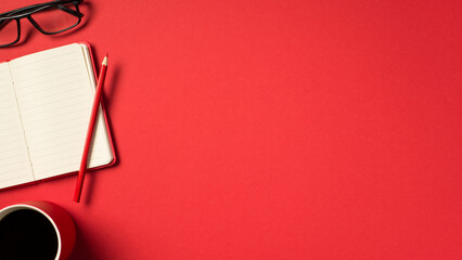 Top view photo of open red organizer pencil glasses and red cup of coffee on isolated vivid red background with copyspace