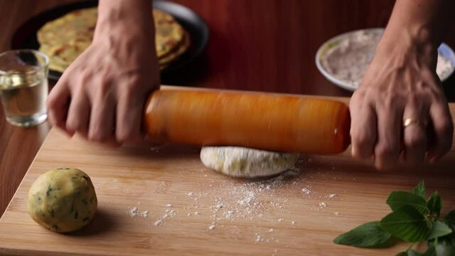 Preparation of Aloo Paratha or roti parantha chapati 4K slow motion video footage Punjab, North India. Female hand rolling whole wheat dough mashed potato stuffing rolling pin vegetarian Indian food
