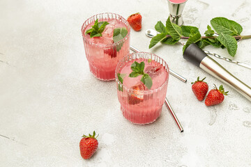 Refreshing summer drink with strawberry slices, mint, and ice in glasses. Berry mojito cocktail or mocktail on the table with copy space. 