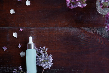 Dropper glass Bottle Mock-Up. Body treatment and spa. Natural beauty products. Template of turquoise serum droplet bottle in the lilac flowers. Natural wellness cosmetic concept. Copy space.