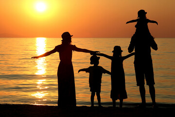 family silhouette at sunset by the sea...