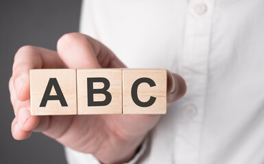 Business man hand holding wooden cube with abc text. Financial, marketing and business concepts - obrazy, fototapety, plakaty