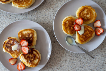 fluffy pancakes on a plate are stuffed with strawberries and poured with jam. thick pancakes for breakfast