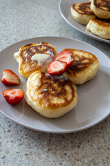 fluffy pancakes on a plate are stuffed with strawberries and poured with jam. thick pancakes for breakfast