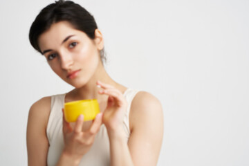 woman with yellow jar of cream cosmetology skin care light background