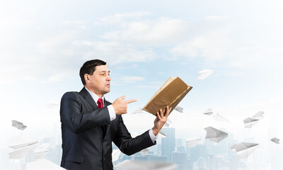 Senior businessman finger pointing into open book