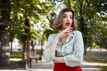 pretty blonde in red skirt outdoors in the park green trees