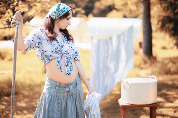 Pregnant woman hanging sheets on the rope for drying